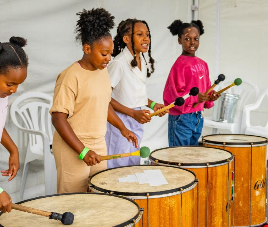 Children taking part in a drumming workshop at Summer Fun 2025